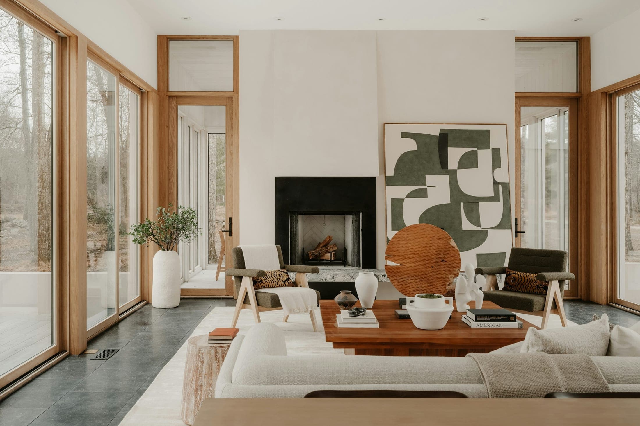 Bright living room with timber-framed glass doors, a black fireplace and a cream sofa
