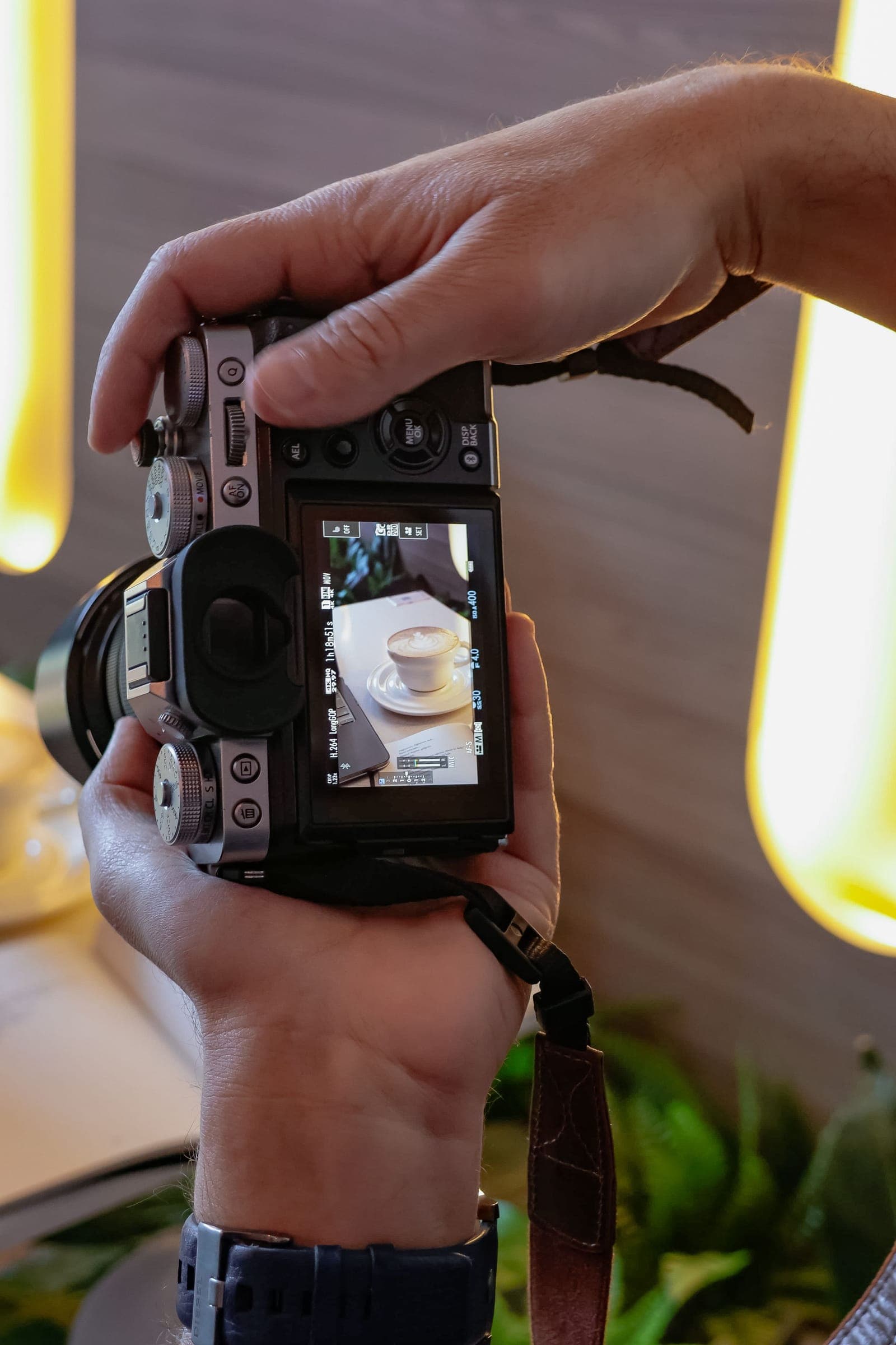 Photographer framing a latte on a compact camera screen during a cafe shoot