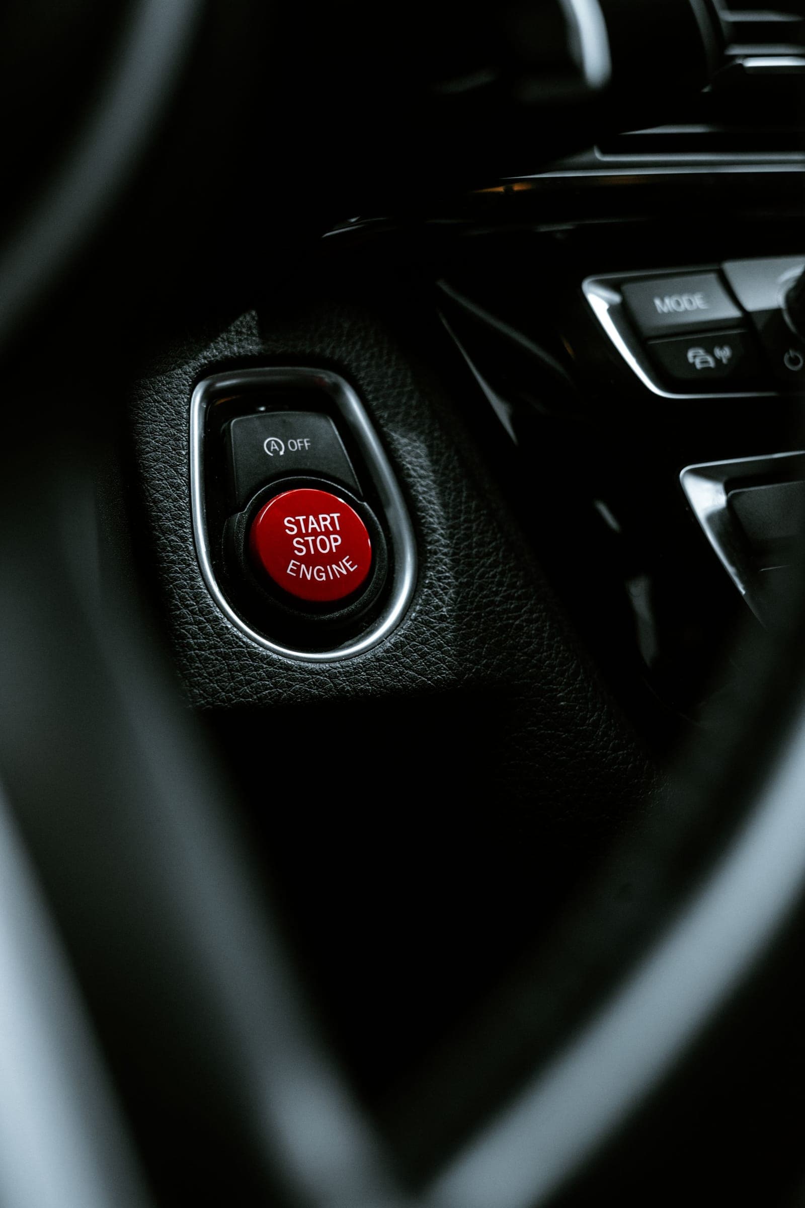 Close-up of a red engine start-stop button on a dark dashboard
